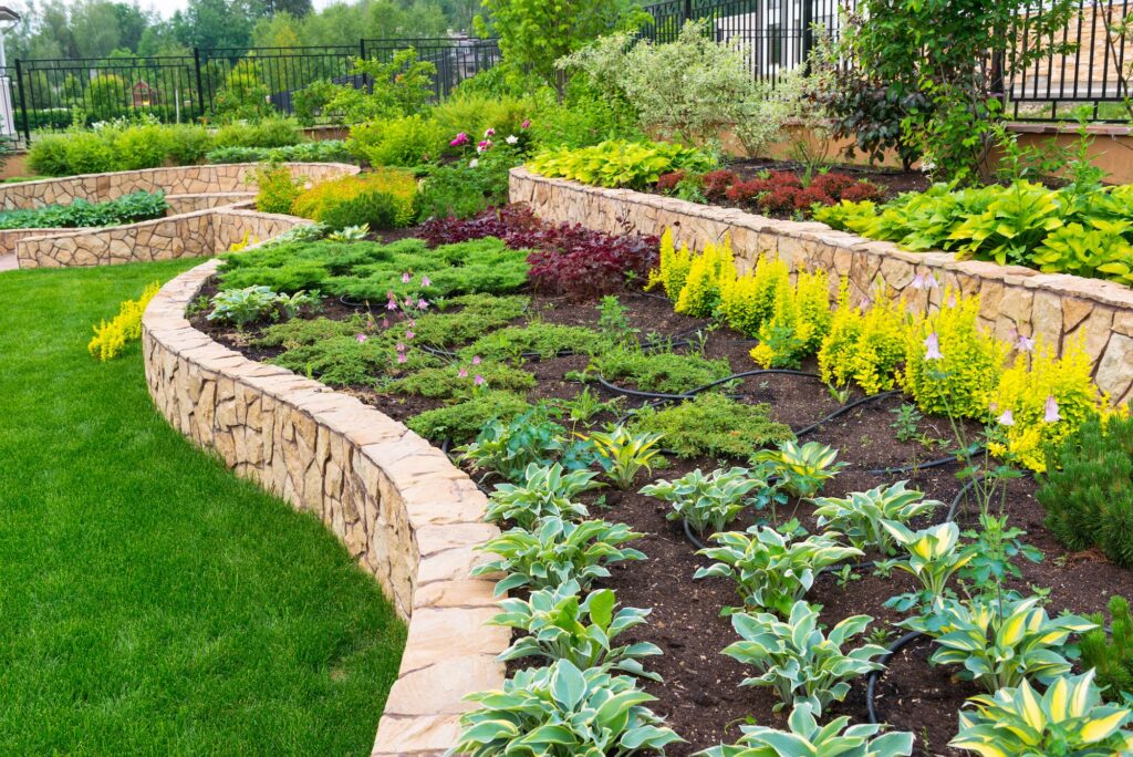 Freshland landscaped raised stone bed of hostas and other complimentary shrubs